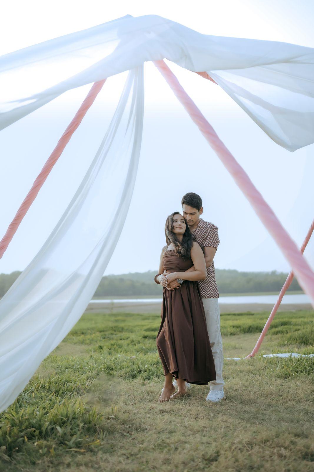 Sheer fabric framing Apeksha and Rakshit in an embrace