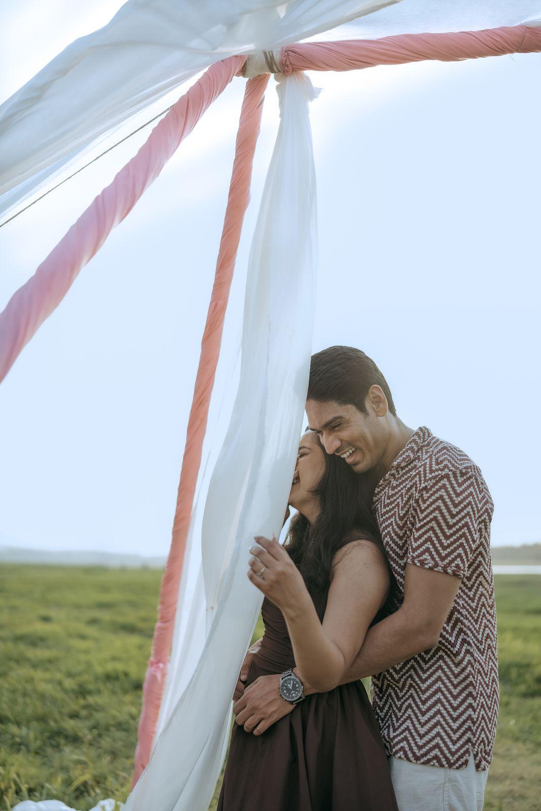 The couple close together beneath the drifting veil